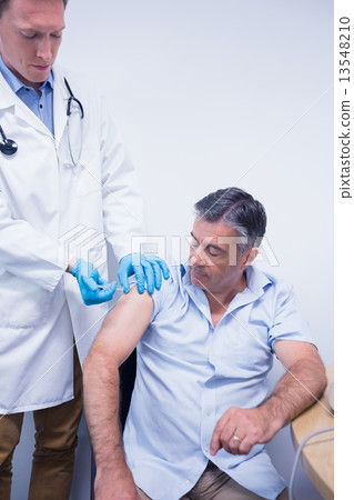 Doctor giving injection to his patient 13548210