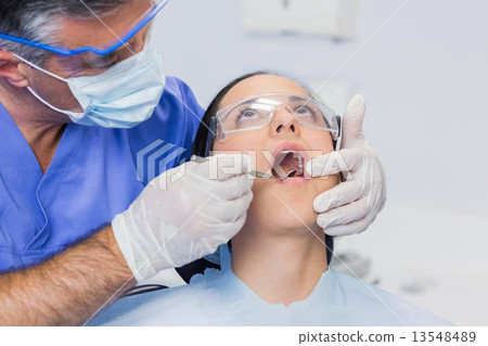 Dentist examining a patient with angle mirror 13548489