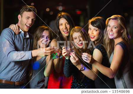 Happy friends drinking shots smiling at camera Happy friends drinking shots smiling at camera 13548696