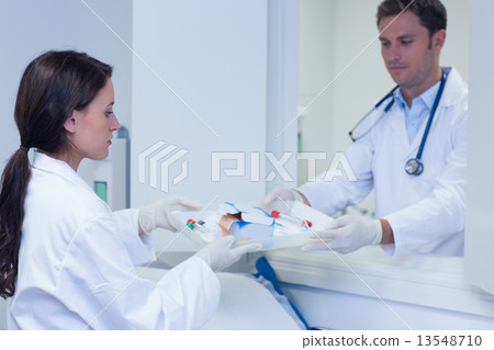 Doctor giving tray with blood sample to his colleague Doctor giving tray with blood sample to his colleague 13548710