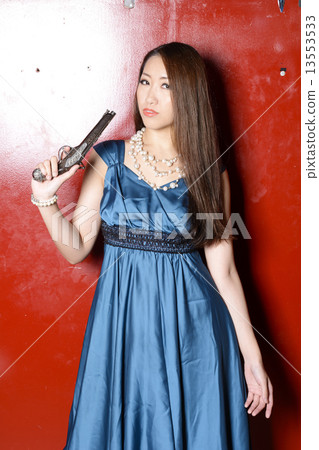 一件燕尾服的一名婦女有站立在紅色牆壁前面的槍的 13553533