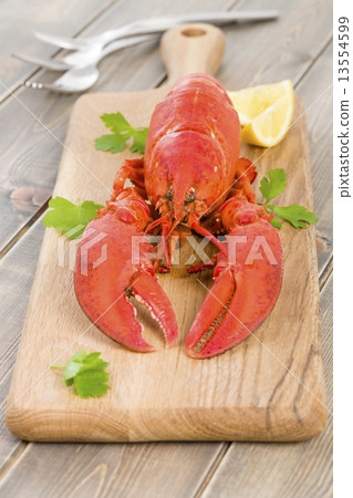 Lobster and lemon wedges on a chopping board.  13554599
