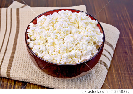 Curd in wooden bowl on board with brown cloth 13558852