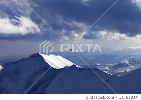 Off-piste slope for heliskiing and helicopter in evening 13563834