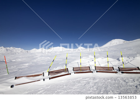 Ski slope and wooden benches in snow 13563853