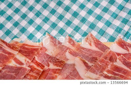 Top view of Serrano ham slices over plate and tablecloth 13566694