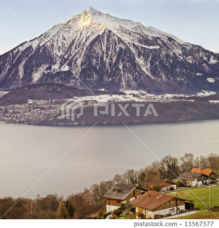Panoramic view over Swiss Apls mountains near the Thun lake in w 13567377