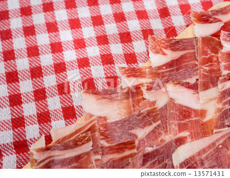 Top view of Serrano ham slices over plate and tablecloth 13571431