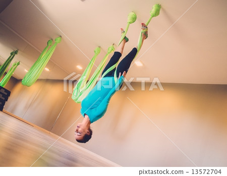 Young woman performing antigravity yoga exercise 13572704