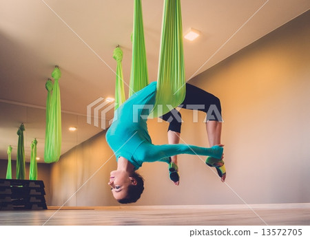 Young woman performing antigravity yoga exercise Young woman performing antigravity yoga exercise 13572705