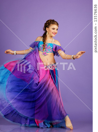 Beautiful belly dancer wearing a purple costume 13576636