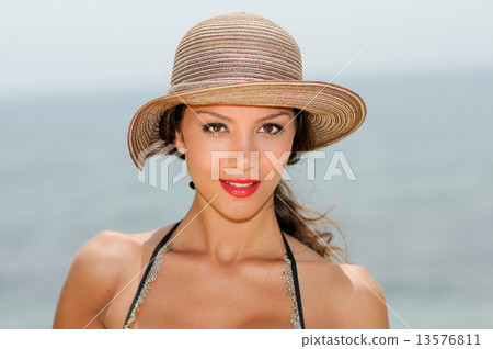 Attractive woman smiling with a sun hat on a tropical beach Attractive woman smiling with a sun hat on a tropical beach 13576811