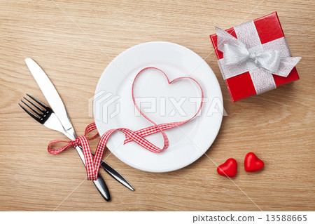 Valentine's Day heart shaped red ribbon over plate with silverwa 13588665