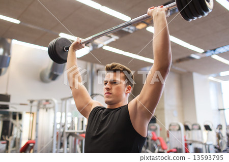 young man flexing muscles with barbell in gym 13593795