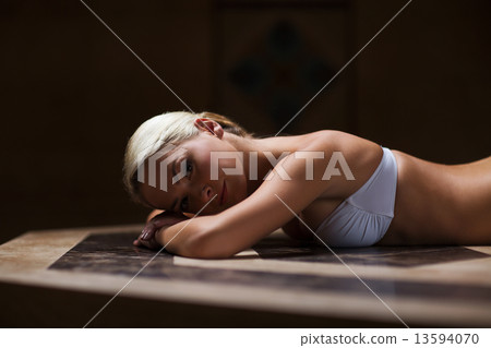 young woman lying on hammam table in turkish bath 13594070