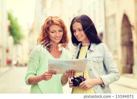 smiling teenage girls with map and camera 13594071