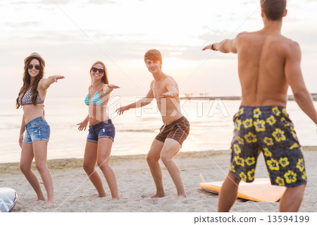 smiling friends in sunglasses with surfs on beach 13594199