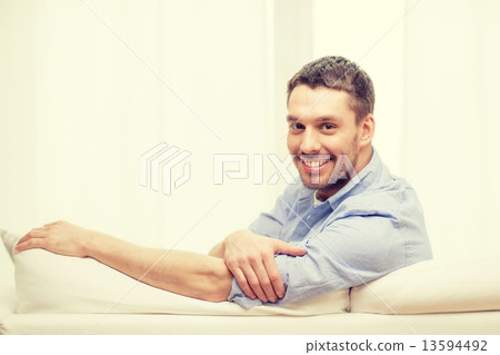 smiling man sitting on sofa at home smiling man sitting on sofa at home 13594492
