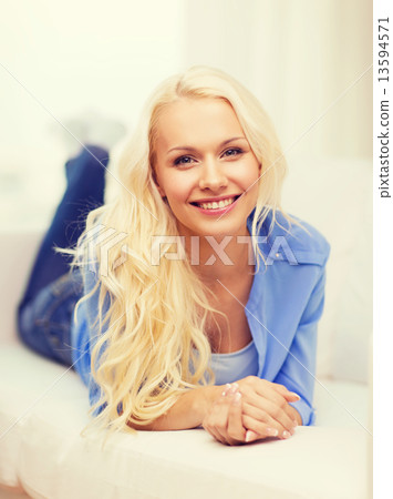 smiling young woman lying on sofa at home 13594571