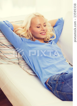 smiling young woman lying on sofa at home 13595338