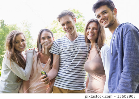 Happy students looking at smartphone outside on campus 13602905