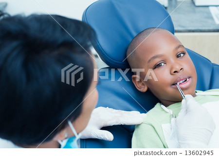 Dentist examining boys teeth in the dentists chair 13602945