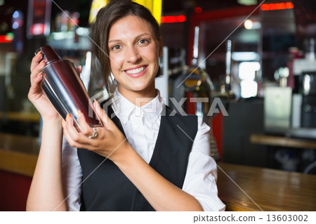Happy barmaid smiling at camera making cocktail 13603002
