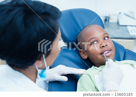 Dentist examining boys teeth in dentists chair 13603185