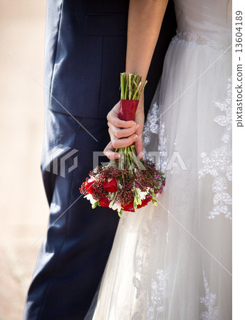 bride hugging groom and holding wedding bouquet 13604189