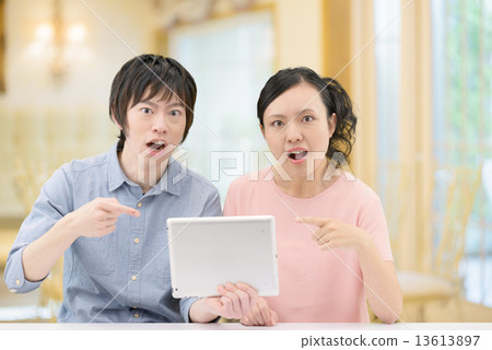 20多歲夫婦誰拿著一台咖啡館的平板電腦 13613897