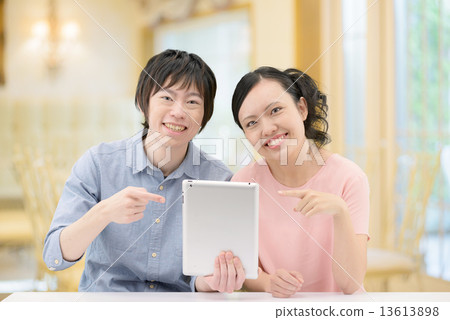 20多歲夫婦誰拿著一台咖啡館的平板電腦 13613898