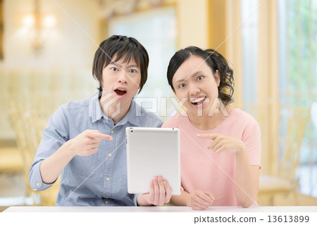 20多歲夫婦誰拿著一台咖啡館的平板電腦 13613899