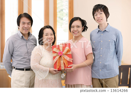Parent and child taking a commemorative photo with a present in the dining room at home Parent and child taking a commemorative photo with a present in the dining room at home 13614266