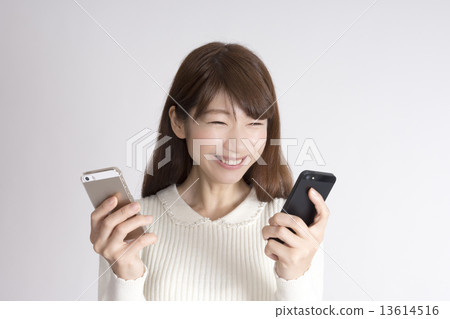 A woman who has two smartphones and a happy A woman who has two smartphones and a happy 13614516