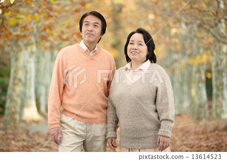 走在一條沿途有樹的大道的一對中年夫婦在秋天 13614523