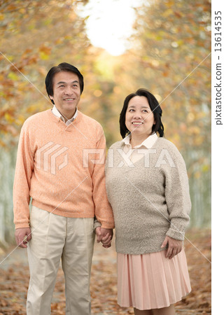 走在一條沿途有樹的大道的一對中年夫婦在秋天 13614535