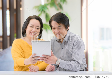 一對中年夫婦穿著休閒服，在家裡的客廳裡操縱著這款平板電腦 13614739