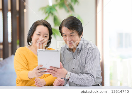 一對中年夫婦穿著休閒服，在家裡的客廳裡操縱著這款平板電腦 13614740