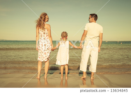 Happy family standing at the beach at the day time Happy family standing at the beach at the day time 13634845