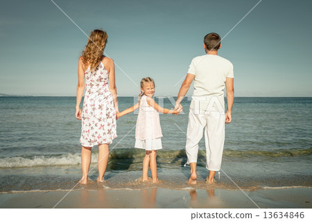 Happy family standing at the beach at the day time Happy family standing at the beach at the day time 13634846