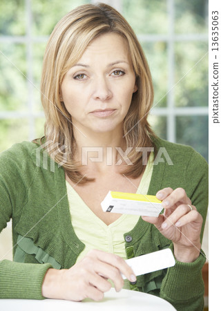 Woman Reading Information On Drug Packaging Woman Reading Information On Drug Packaging 13635063