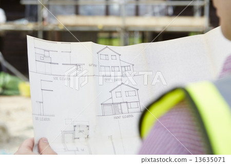 Architect On Building Site Looking At Plans For House 13635071