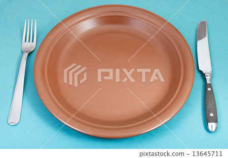 brown ceramic plate with fork and knife on green brown ceramic plate with fork and knife on green 13645711