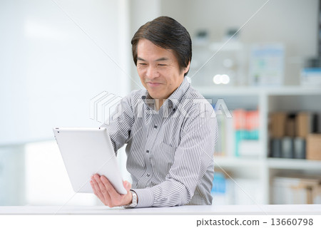 Middle-aged men in casual wear, who are manipulating tablets indoors Middle-aged men in casual wear, who are manipulating tablets indoors 13660798