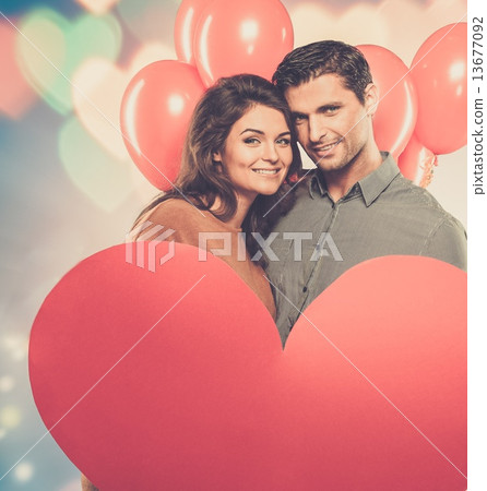 Couple holding handmade paper heart and red balloons Couple holding handmade paper heart and red balloons 13677092