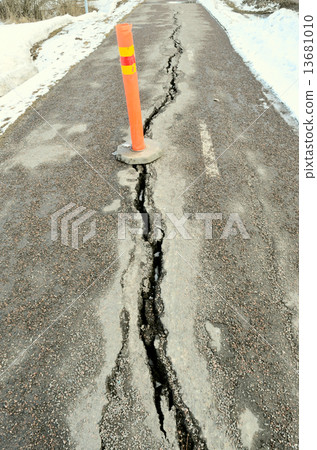 long crack stretching cross the sidewalk  with orange sign 13681010