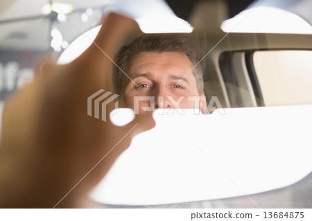 Man looking in an interior car mirror Man looking in an interior car mirror 13684875