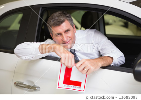Cheerful male driver tearing up his L sign 13685095