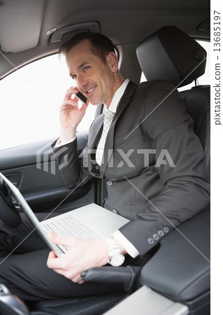 Businessman working in the drivers seat 13685197