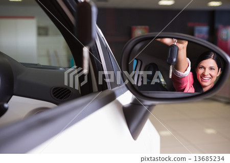 Woman showing car key in rear view mirror 13685234